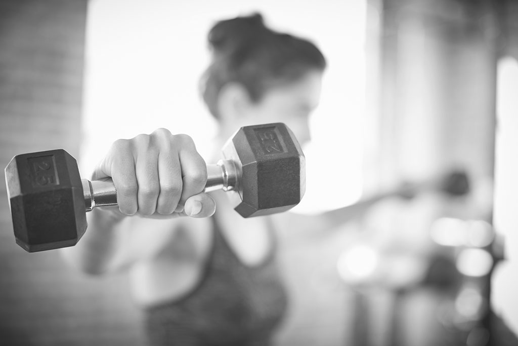 Close-up of dumbbell held by young woman in gym
